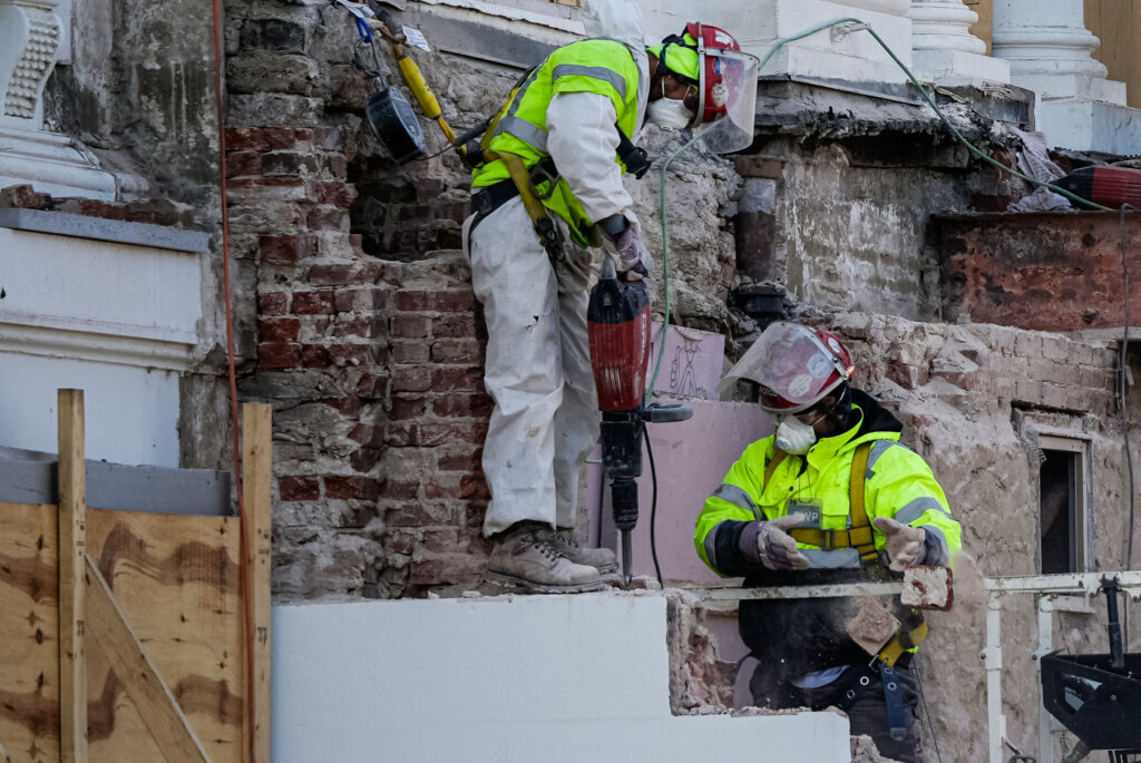 A worker, right, throws bricks as construction of a new ballroom continues on the East Wing of the White House, Monday, Dec. 1, 2025, in Washington. (AP Photo/Julia Demaree Nikhinson)