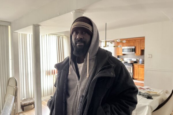 man stands heavily bundled in winter clothing in apartment unit