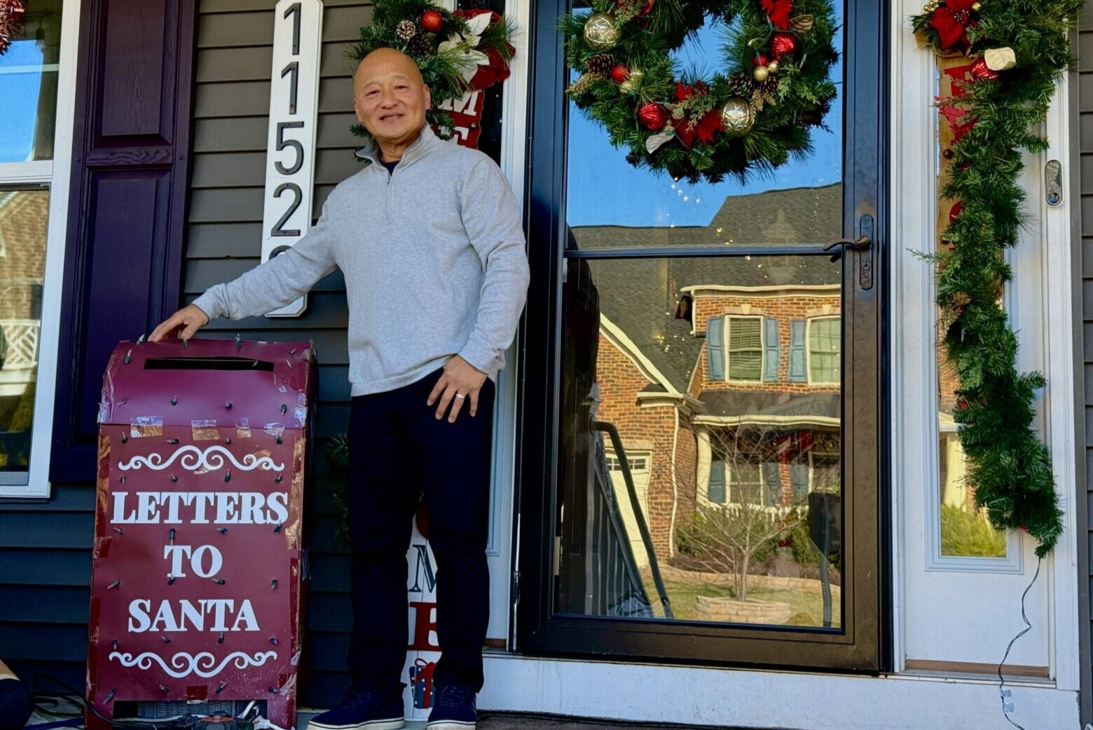a man stands with arm around mailbox on front porch