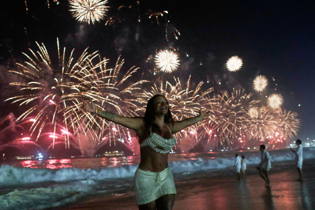 A woman celebrates as fireworks light up the sky over Copacabana Beach during New Year's celebrations in Rio de Janeiro, Thursday, Jan. 1, 2026. (AP Photo/Bruna Prado)