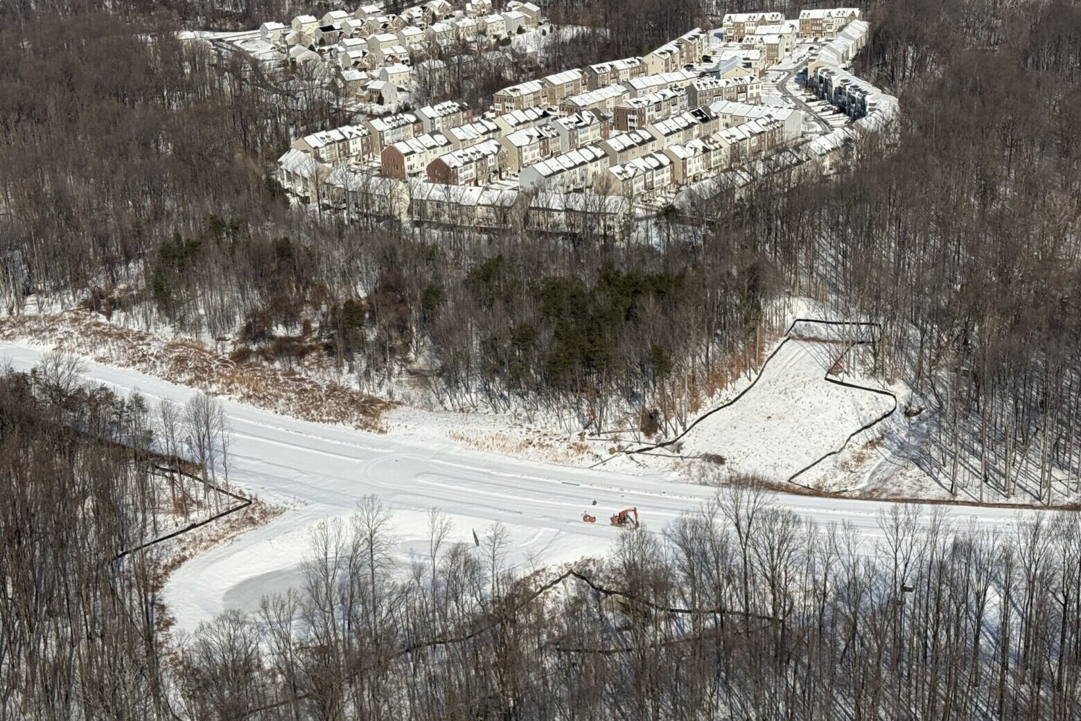 an aerial view of partially wooded suburban area with snow on ground
