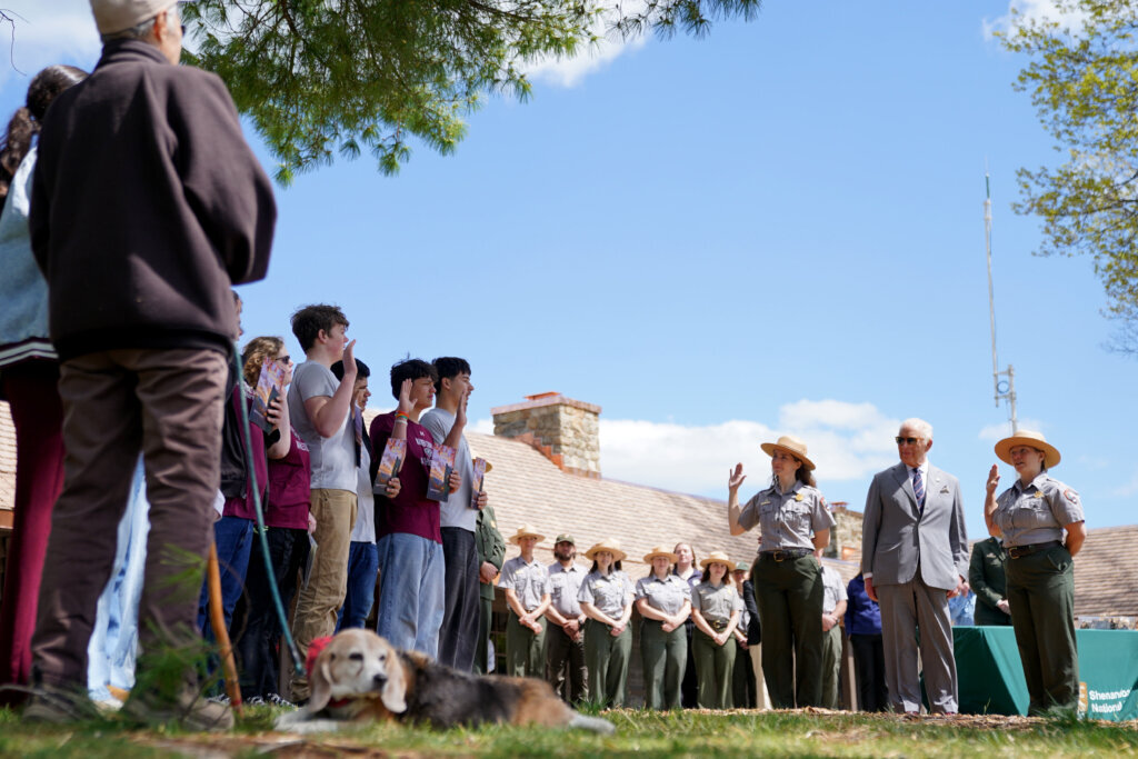 Britain's King Charles III looks on as students from Warren County High School are sworn in as junior park rangers, as they visit Shenandoah National Park in Front Royal, Virginia, Thursday, April 30, 2026. Bailey, the dog, foreground, is a BARK ranger. (AP Photo/Allison Robbert, Pool)